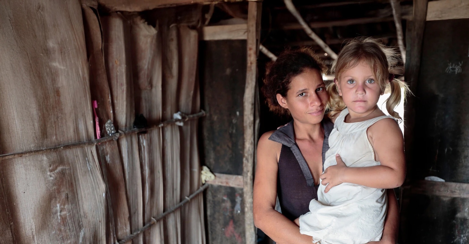 A mother holds her daughter in the doorway of their home in Cuba